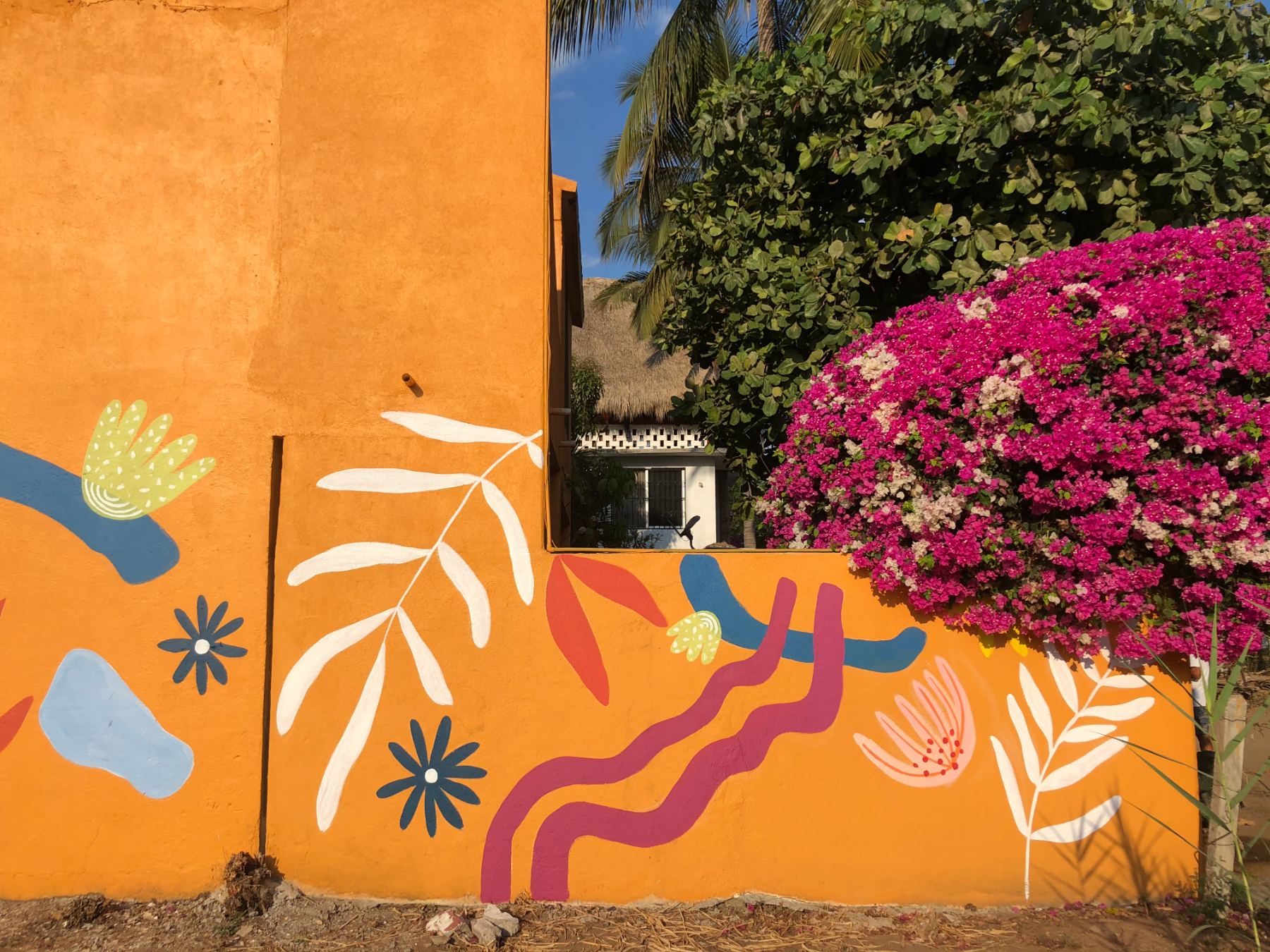 Hand-painted orange garden wall mural at Casa Mango in Puerto Escondido, Oaxaca, Mexico by Scout Hill Co