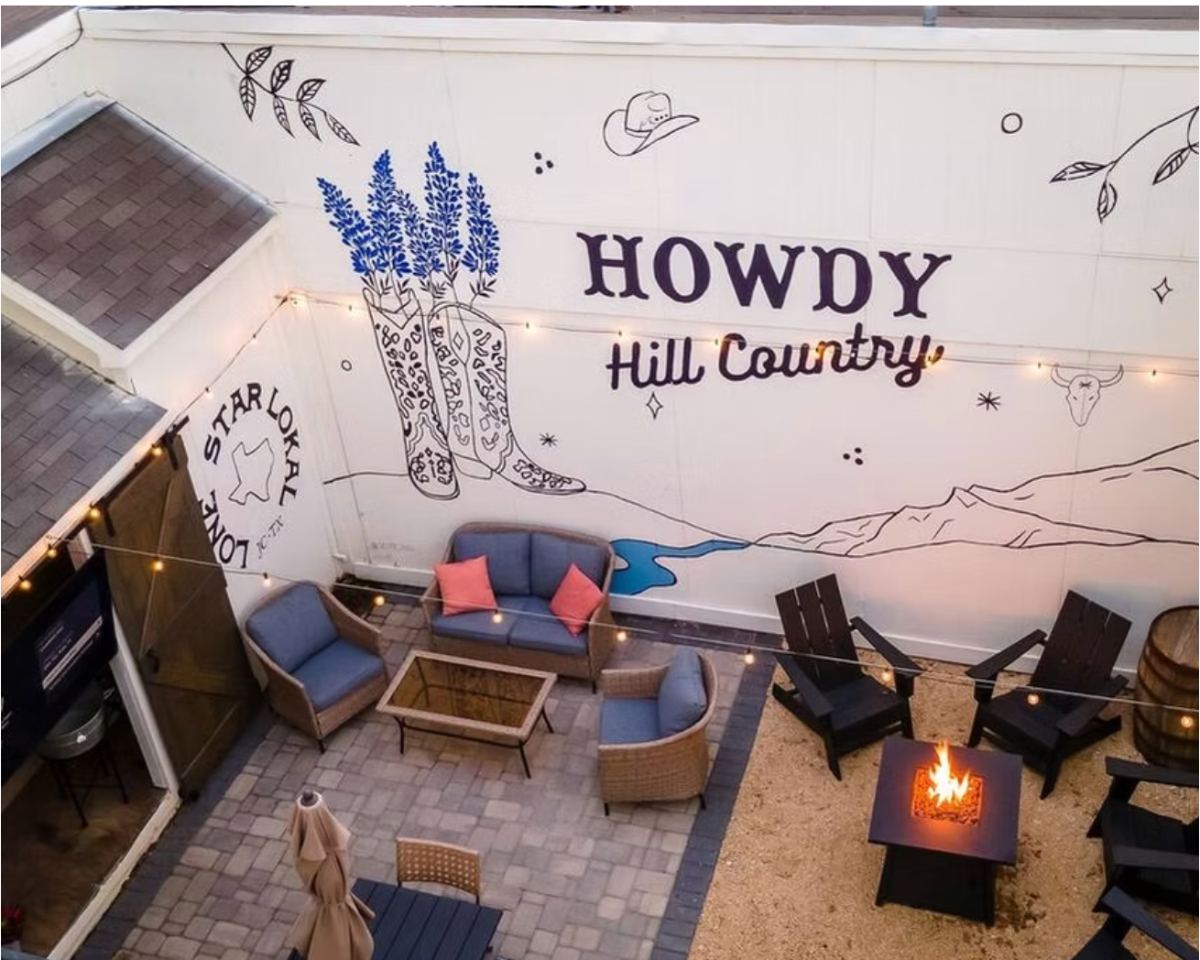 Courtyard mural reading Howdy Hill Country with bluebonnets in cowboy boots — hand-painted mural in Johnson City, Texas by Scout Hill Co