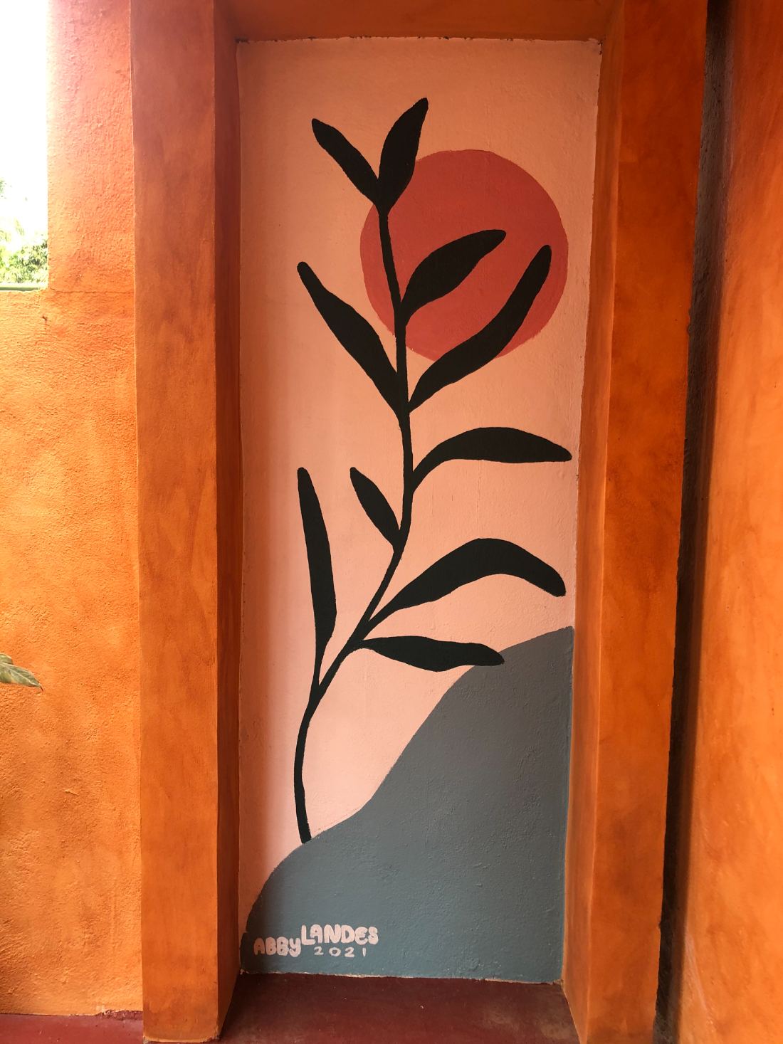 Alcove mural of a black branch against a coral sun and slate hill — hand-painted mural in Oaxaca, Mexico by Scout Hill Co